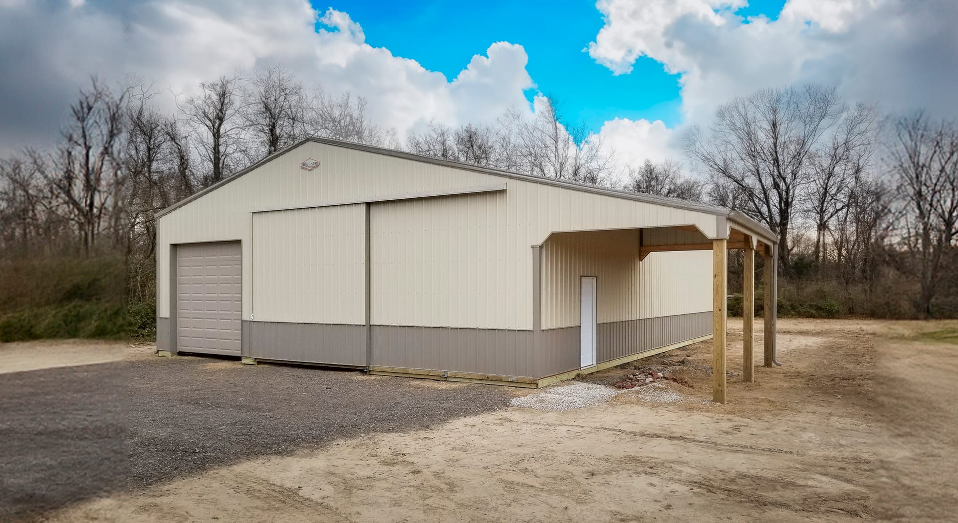 A light-colored post-frame building is shown with a gable roof and vertical siding. It features a large overhead garage door on the front, ideal for vehicle storage or a workshop. A smaller pedestrian door is present on the side, under a canopy supported